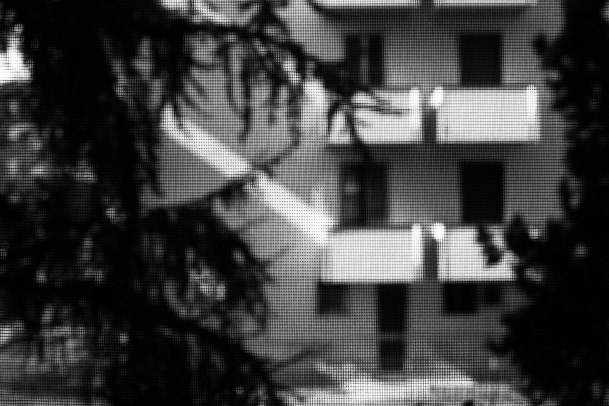 fotografia in bianco e nero di un condominio visto da una zanzariera